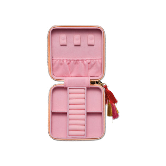 Travel jewelry case with tassels resting open displaying places for jewelry on white background