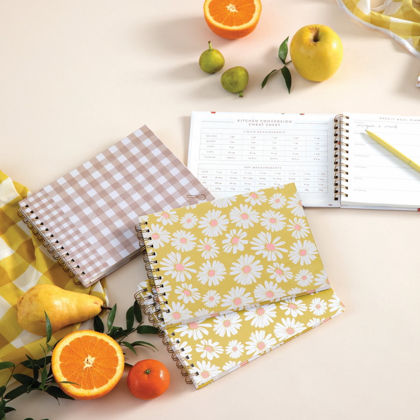 Lifestyle image of multiple planners open on table and surrounded by fruit and market bag.