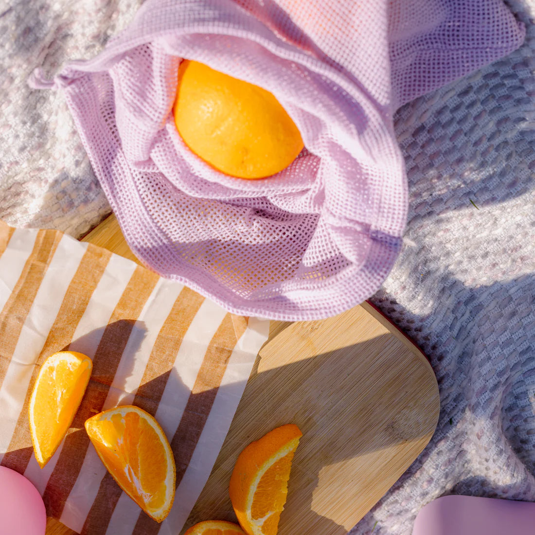 Picnic set up with a chopping board, oranges and market bag.